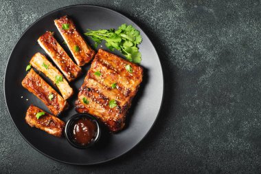 Barbekü soslu bir tabakta servis edilen sıcak ızgara pirzola. Üst Manzara. Boşluğu kopyala.