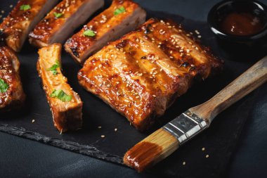 Barbekü domuz pirzolası ve siyah arka planda sıcak bal biberli terbiye..