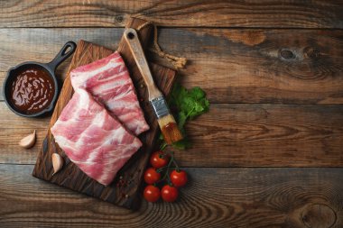 Baharatlı çiğ domuz pirzolası, siyah ahşap arka planda tuz ve biberiye. Kopyalama alanı olan üst görünüm.