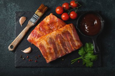 Barbekü, çiğ domuz pirzolası ve barbekü sosu hazır. Siyah arka plan. Üst görünüm.