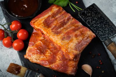 Barbekü, çiğ domuz pirzolası ve barbekü sosu hazır. Siyah arka plan. Üst görünüm.