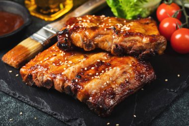 Barbekü domuz pirzolası ve siyah arka planda sıcak bal biberli terbiye..