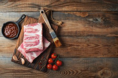 Baharatlı çiğ domuz pirzolası, siyah ahşap arka planda tuz ve biberiye. Kopyalama alanı olan üst görünüm.