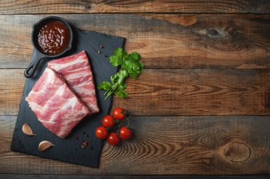Baharatlı çiğ domuz pirzolası, siyah ahşap arka planda tuz ve biberiye. Kopyalama alanı olan üst görünüm.
