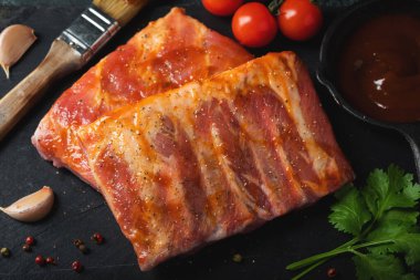 Barbekü, çiğ domuz pirzolası ve barbekü sosu hazır. Siyah arka plan. Üst görünüm.