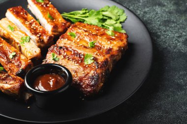 Barbekü soslu bir tabakta servis edilen sıcak ızgara pirzola. Üst Manzara. Boşluğu kopyala.