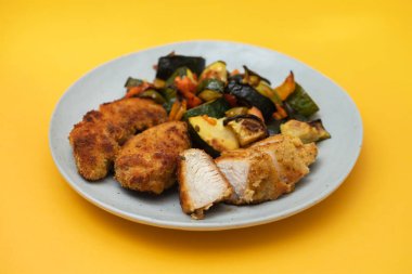 Lezzetli kızarmış tavuk göğsü şeritleri ve beyaz tabakta fırında sebzeler.