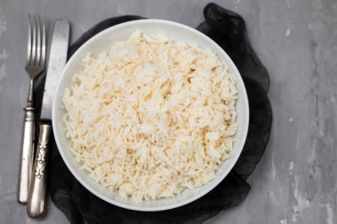 Boiled rice in a bowl on gray ceramic background.