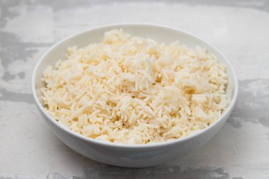 Boiled rice in a bowl on gray ceramic background.