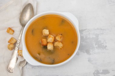 Gri seramik üzerinde beyaz kasede kraker bulunan sebze çorbası.