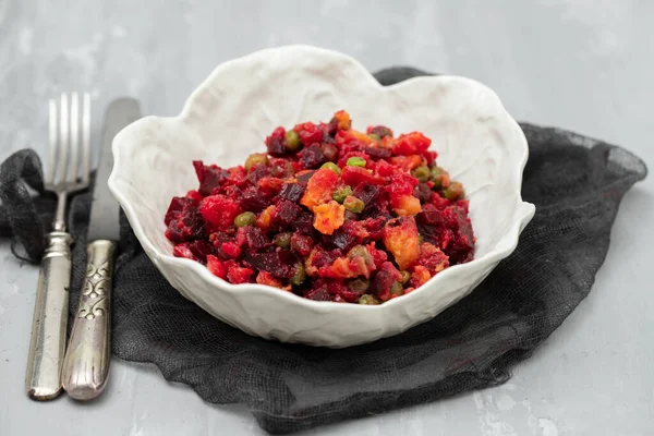 Beetroot and boiled vegetables, traditional Russian homemade salad in white bowl.