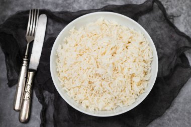 Boiled rice in a bowl on gray ceramic background.