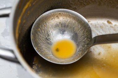 a cooking pot and kitchen spoon after use for vegetable soup