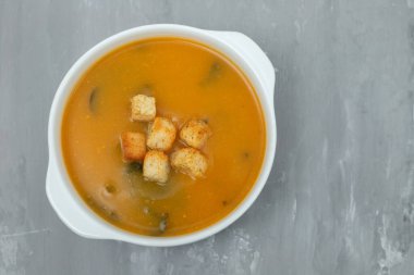 Gri seramik üzerinde beyaz kasede kraker bulunan sebze çorbası.