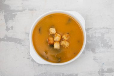 Gri seramik üzerinde beyaz kasede kraker bulunan sebze çorbası.