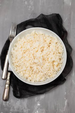 Boiled rice in a bowl on gray ceramic background.