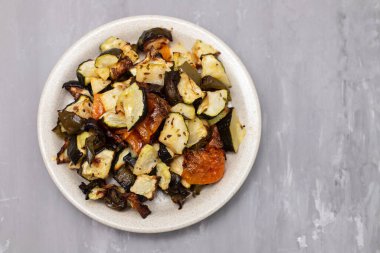 Mixed baked vegetables on light brown dish on ceramic