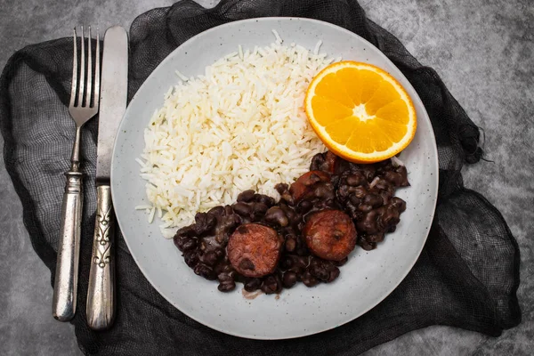 Typical brazilian food beans with sausages and rice Feijoada on white big dish