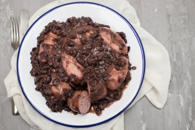 black beans stew with sausages on a big white dish