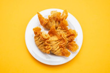 Fried wan tan on white small plate on yellow
