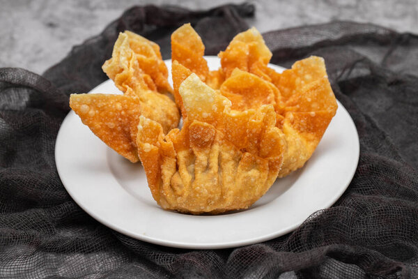 Fried wan tan on white small plate on dark