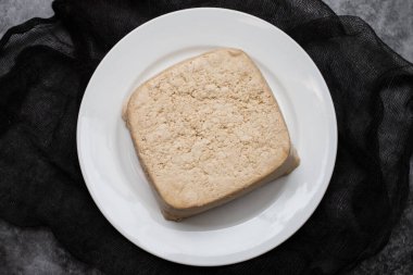 raw tofu block on white small dish on gray ceramic