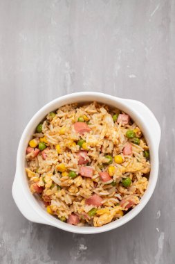 Rice with corn. peas, ham on white small bowl