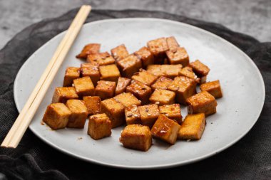 crispy deep stir fried tofu cubes on small white dish