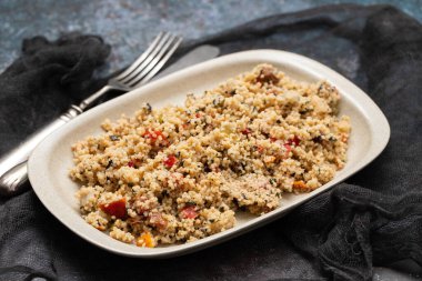 Couscous with vegetables in a dish with fork and knife