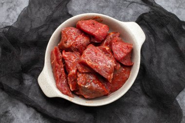 Fresh raw cube of beef in white bowl on ceramic