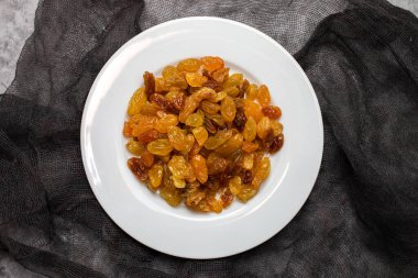 Yellow golden raisins in white ceramic plate on ceramic