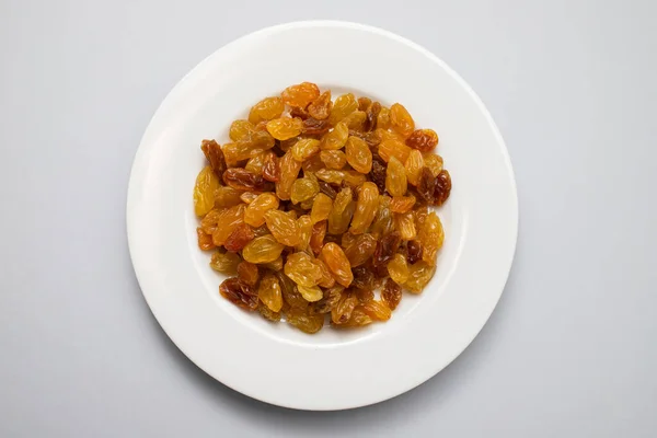 Stock image Yellow golden raisins in white ceramic plate on gray paper