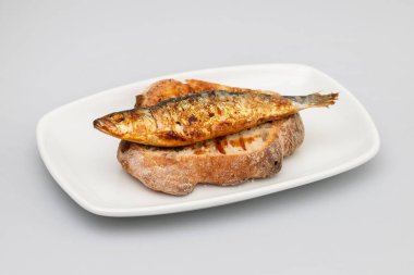 Izgara sardalya soslu beyaz tabakta taze ekmek.