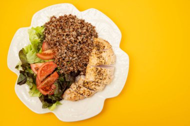 Karabuğdaylı fırında hindi ve beyaz tabakta taze sebze salatası.