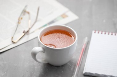 Gazeteler ve okuma gözlüklü beyaz çay fincanı..