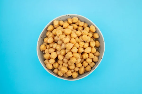 Stock image Ceramic bowl full of chickpeas, boiled and drained on blue