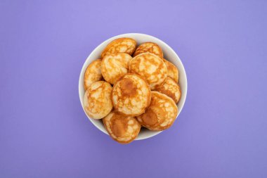 Beyaz kasede parlak arka planda mini mısır gevreği yığını..