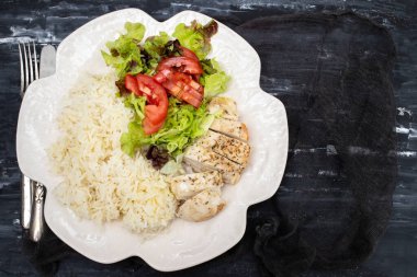 Diyet yemek. Haşlanmış pirinçli tavuk göğsü ve beyaz tabakta salata. Sağlıklı bir yaşam tarzı. Spor beslenmesi.