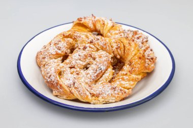 Beyaz büyük tabakta kremalı ve şekerli Bretzel.