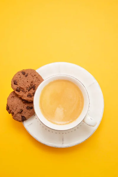 黄色の紙にチョコチップをかけたコーヒーカップ — ストック写真