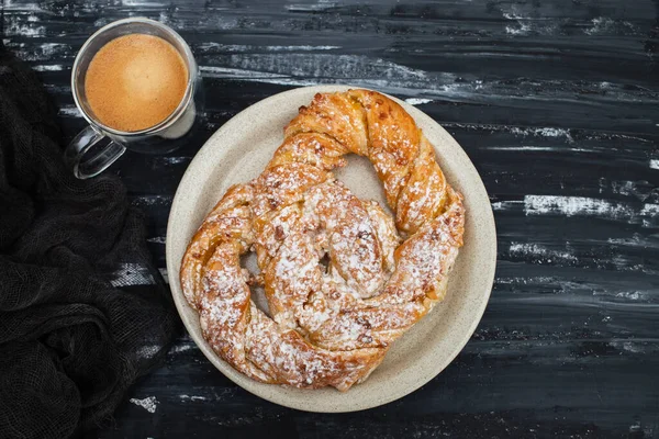 Beyaz büyük tabakta kremalı ve şekerli Bretzel.