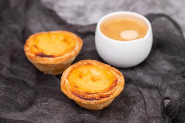 Yumurtalı tart, geleneksel Portekiz tatlısı, pastel de nata ve bir fincan kahve.