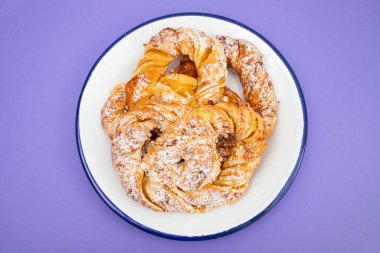 Beyaz büyük tabakta kremalı ve şekerli Bretzel.