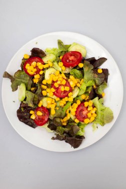 Domateslerden, konserve mısırdan, salatalıktan ve maruldan yapılmış lezzetli hafif sebze salatası.