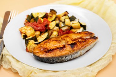 Siyah tabakta sebzeli kızarmış somon.