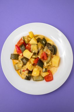 Lezzetli sebze karışımı, kabak, kırmızı biber, beyaz tabakta patates ve domates.