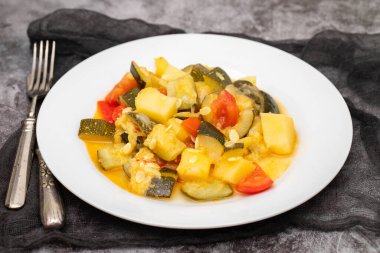 Lezzetli sebze karışımı, kabak, kırmızı biber, beyaz tabakta patates ve domates.