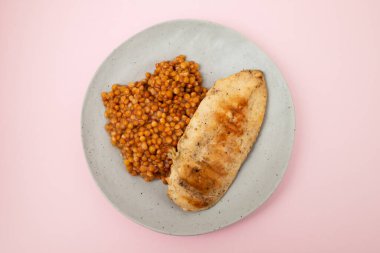 Bir kase haşlanmış kırmızı mercimek ve beyaz seramik kasede tavuk göğsü.