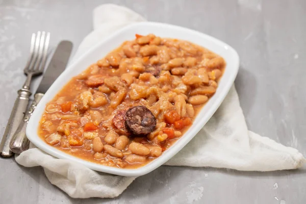 typical portuguese dish dobrada with beans in white dish on dark background