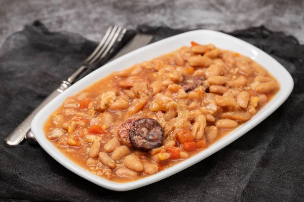 typical portuguese dish dobrada with beans in white dish on dark background